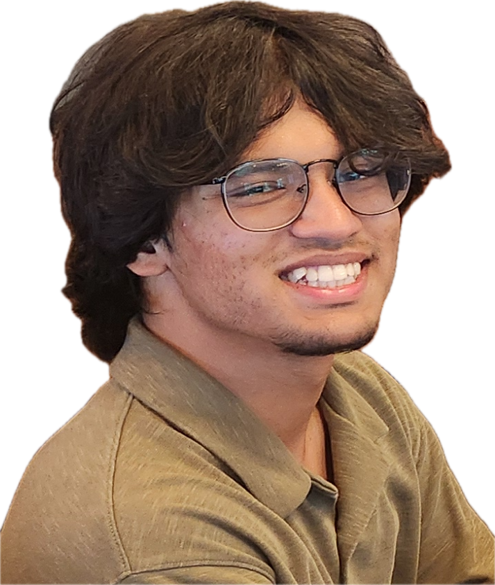A photo of Nafees Abdullah. He has brown skin, shaggy hair, and facial hair on his chin. Nafees is wearing round glasses and a olive a collared shirt. He is smiling at the camera.